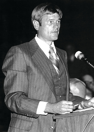 A photo of Tom at a podium speaking