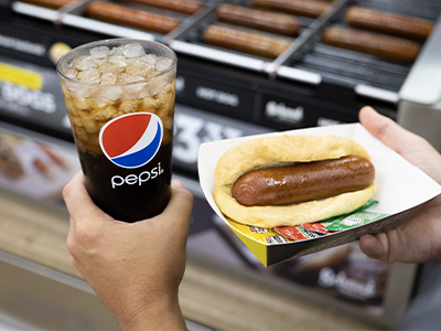 Love's hot dog in tray next to glass Pepsi cup
