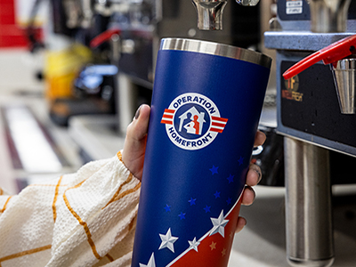 Loves customer holding Operation Homefront tumbler at coffee urn