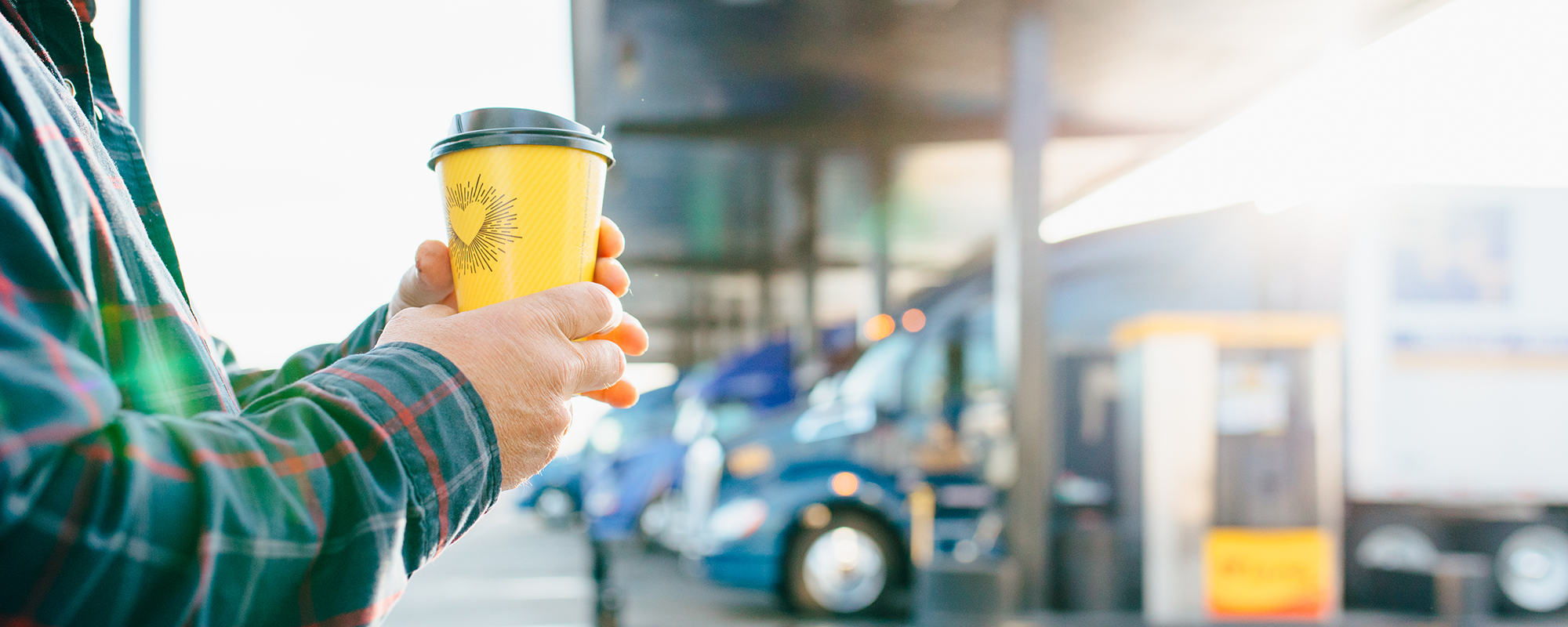A driver holding a coffee cup in front of the diesel fueling bay 
