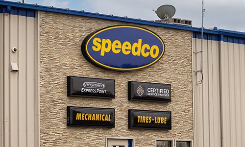 A photo of the exterior of a Speedco repair shop with various mechanical signs on the front