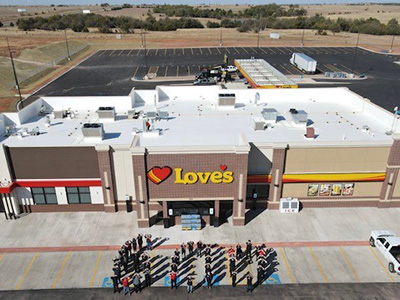 Love's Travel Stop store front, with employees standing in front making a 600.